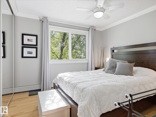 Bedroom featuring natural light, wood-finish flooring, mirrored closet doors, a ceiling fan, and crown molding - 301 10003 87 Avenue, Edmonton, AB - Indoor Photo Showing Bedroom