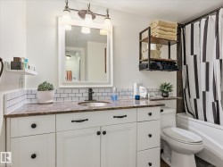 Bathroom vanity featuring white cabinetry, a brown speckled countertop, and subway tile backsplash - 