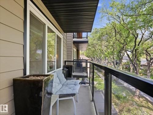 Balcony featuring glass panel railings, a concrete floor, and a black slatted ceiling - 301 10003 87 Avenue, Edmonton, AB - Outdoor With Exterior