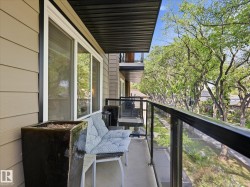 Balcony featuring glass panel railings, a concrete floor, and a black slatted ceiling - 