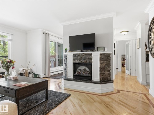 Corner gas fireplace with a stacked stone facade and a white mantel - 301 10003 87 Avenue, Edmonton, AB - Indoor Photo Showing Living Room With Fireplace