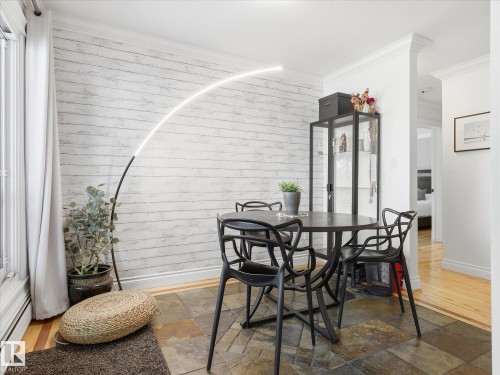 Dining area featuring a textured shiplap accent wall and natural stone tile flooring - 301 10003 87 Avenue, Edmonton, AB - Indoor