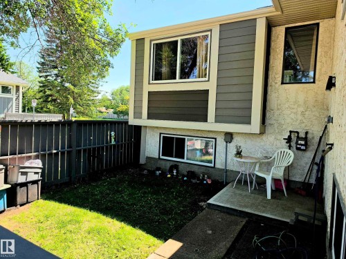 Exterior property featuring stucco and horizontal siding, multiple windows, a small concrete patio, and a fenced grassy area - 600 Willow Crest, Edmonton, AB 