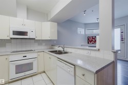 Kitchen featuring light cabinetry, white appliances, a double basin sink, and tile flooring - 