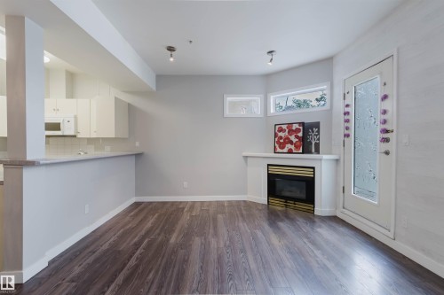 Open-concept living area with dark wood-finish flooring - 202 10939 82 Avenue, Edmonton, AB 