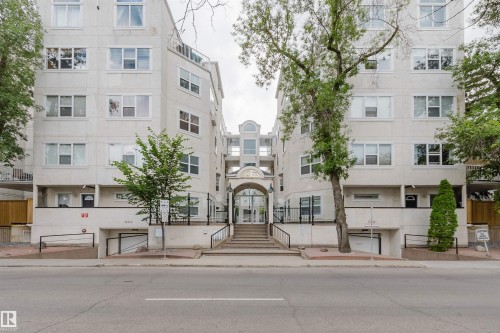 Building exterior featuring an arched main entrance, multiple windows, and a subterranean parking entrance - 202 10939 82 Avenue, Edmonton, AB 
