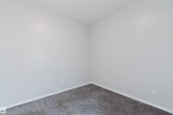Room featuring light gray walls, white baseboards, and gray textured carpeting - 