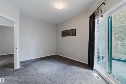 Carpeted room featuring a ceiling-mounted light fixture, light gray wall paint, and white baseboards - 202 10939 82 Avenue, Edmonton, AB 