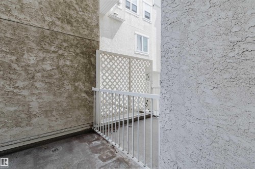 Private patio space featuring a lattice privacy screen and white metal railing - 202 10939 82 Avenue, Edmonton, AB 