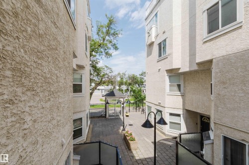 Outdoor paved courtyard featuring a covered gazebo, integrated planter boxes, and exterior lighting fixtures - 202 10939 82 Avenue, Edmonton, AB 