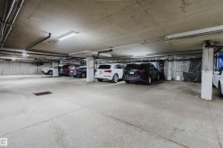Concrete parking garage with exposed ceiling pipes and fluorescent lighting fixtures - 