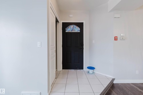 Foyer featuring a dark entry door with decorative glass, tile flooring, and a sliding closet door - 202 10939 82 Avenue, Edmonton, AB 