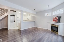 Wood-finish flooring throughout, featuring a built-in fireplace with a white mantel, recessed lighting, and a kitchen bar area - 