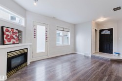 Spacious room featuring wood-finish flooring, a white mantel fireplace with a black and gold insert, and multiple windows for abundant light - 