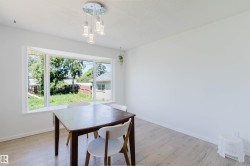 Bright interior room featuring a wide bay window overlooking a private backyard - 