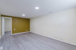 Spacious room featuring light wood-finish flooring, recessed lighting, and a neutral color palette with an accent wall - 