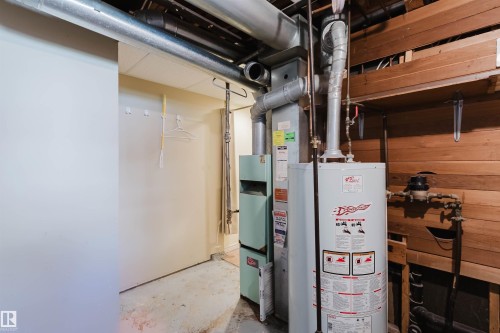 Utility area featuring a water heater, furnace, exposed ductwork, and wood paneling - 9606 163 Street, Edmonton, AB 
