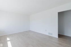 Spacious interior featuring light wood-finish flooring and bright white walls - 