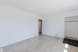 Bright, open room featuring light wood-finish flooring and white painted walls - 