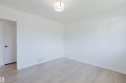 Interior room featuring light wood-finish flooring, white walls, and a contemporary flush-mount ceiling light - 