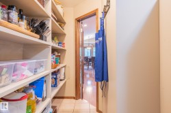 Pantry with built-in shelving, tiled flooring, and a wood-trimmed doorway - 