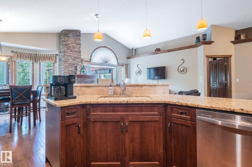 Kitchen island with wood-finish cabinetry and granite countertop - 19 Newton Place, St. Albert, AB - Indoor Photo Showing Kitchen