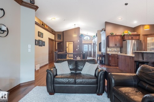 Open-concept living area featuring rich wood-finish flooring, a kitchen with stainless steel appliances, dark wood cabinetry, and a granite-style countertop - 19 Newton Place, St. Albert, AB - Indoor Photo Showing Living Room