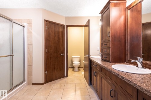 Bathroom featuring a double vanity with integrated sinks, wood cabinetry, and a textured countertop - 19 Newton Place, St. Albert, AB - Indoor Photo Showing Bathroom