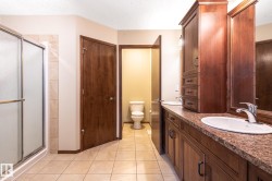 Bathroom featuring a double vanity with integrated sinks, wood cabinetry, and a textured countertop - 
