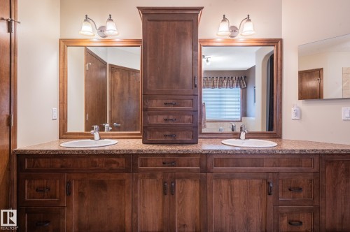 Double vanity featuring wood-finish cabinetry, a patterned countertop, and two framed mirrors - 19 Newton Place, St. Albert, AB - Indoor Photo Showing Bathroom