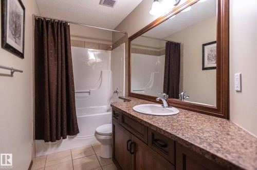 Bathroom featuring a vanity with an integrated sink, a large framed mirror, and a combination shower and tub - 19 Newton Place, St. Albert, AB - Indoor Photo Showing Bathroom