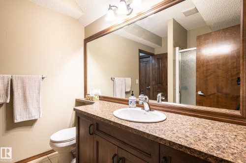 Bathroom vanity featuring a speckled countertop, integrated white sink, and dark wood-finish cabinetry - 19 Newton Place, St. Albert, AB - Indoor Photo Showing Bathroom