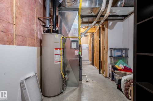 Unfinished basement utility area featuring a water heater, furnace, exposed wood framing, and concrete flooring - 19 Newton Place, St. Albert, AB - Indoor Photo Showing Basement
