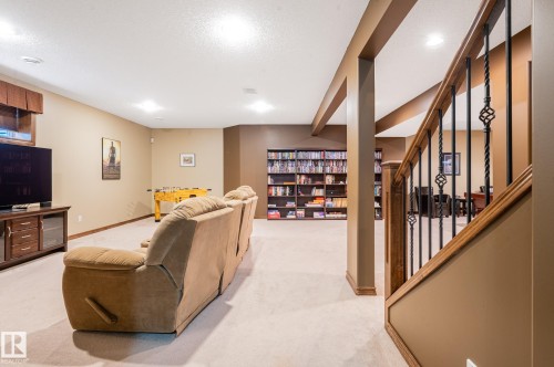 Finished lower level featuring carpeted flooring, recessed lighting, built-in shelving, a wood-finish staircase with wrought iron spindles, and a window with a wood valance - 19 Newton Place, St. Albert, AB - Indoor