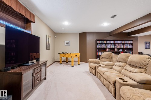 Spacious recreation room featuring light-toned carpet flooring, recessed lighting, and a built-in media storage unit - 19 Newton Place, St. Albert, AB - Indoor Photo Showing Other Room
