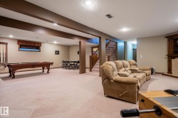 Spacious finished lower level featuring recessed lighting, exposed ceiling beams, and light-toned carpeting - 