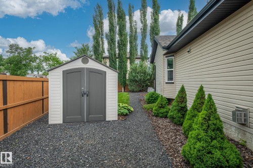 Gravel pathway leading to a two-tone storage shed with arched double doors - 19 Newton Place, St. Albert, AB - Outdoor With Exterior