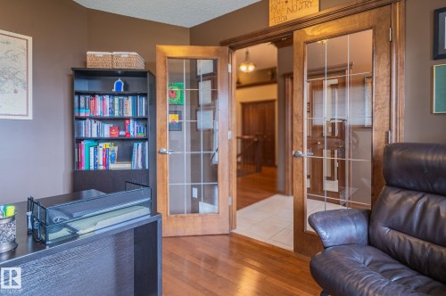 Room featuring wood-finish flooring, French doors with grid-patterned glass, and a built-in bookshelf - 19 Newton Place, St. Albert, AB - Indoor