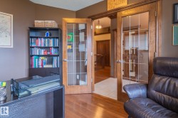 Room featuring wood-finish flooring, French doors with grid-patterned glass, and a built-in bookshelf - 