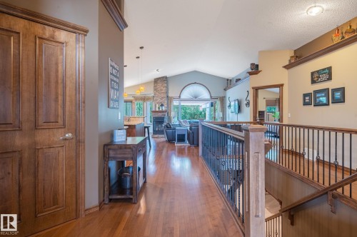 Open concept living area featuring a vaulted ceiling, wood-finish flooring, and a stone-clad fireplace - 19 Newton Place, St. Albert, AB - Indoor Photo Showing Other Room