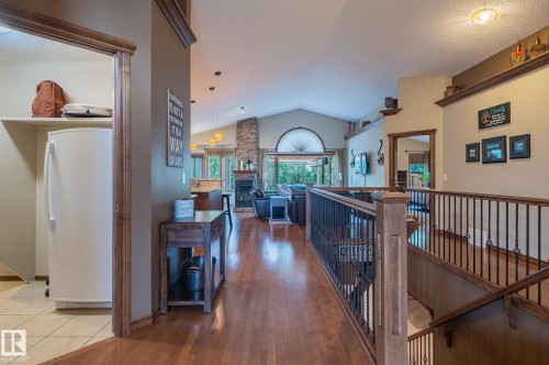 Expansive interior featuring rich wood-finish flooring, a vaulted ceiling, and a stone-clad fireplace - 19 Newton Place, St. Albert, AB - Indoor Photo Showing Other Room