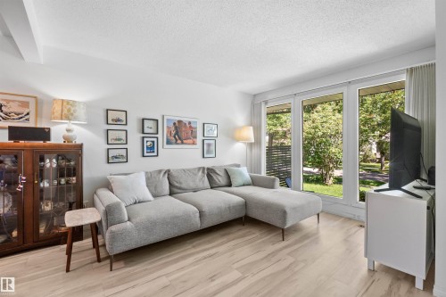Living area featuring light wood-finish flooring, white walls, and a beamed ceiling - 10940 123 Street, Edmonton, AB 