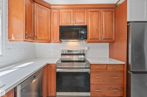 Kitchen featuring wood-finish cabinetry, white subway tile backsplash, and light-toned countertops - 10940 123 Street, Edmonton, AB 