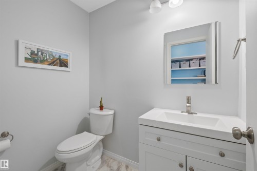 Bathroom featuring a white vanity with integrated sink, brushed nickel faucet, and a wall-mounted mirror - 10940 123 Street, Edmonton, AB 
