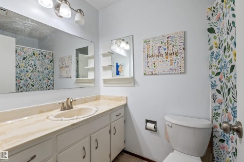 Bathroom featuring an integrated vanity sink with a stone-finish countertop, white cabinetry, and a full-width mirror - 10940 123 Street, Edmonton, AB 