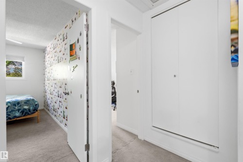 Hallway featuring light gray carpet, white walls, and a bi-fold closet door - 10940 123 Street, Edmonton, AB 
