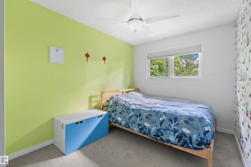 Interior room featuring light green and white painted walls, a window with a white frame, and a white ceiling fan - 10940 123 Street, Edmonton, AB 