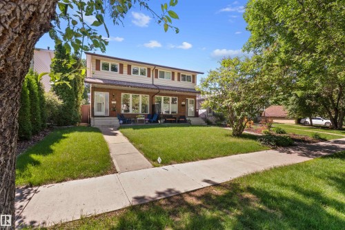 Brick facade townhome with a concrete walkway, established front lawn, and mature trees - 10940 123 Street, Edmonton, AB 