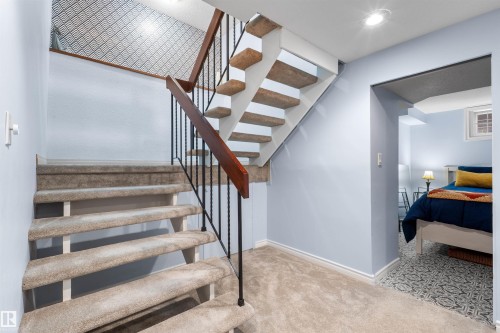 Carpeted staircase with black wrought iron railing and wood-finish banister - 10940 123 Street, Edmonton, AB 