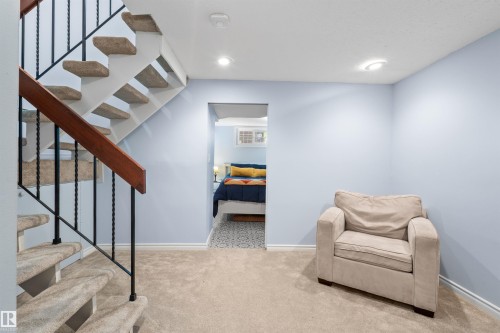 Carpeted staircase with black wrought iron balusters and a wood handrail - 10940 123 Street, Edmonton, AB 